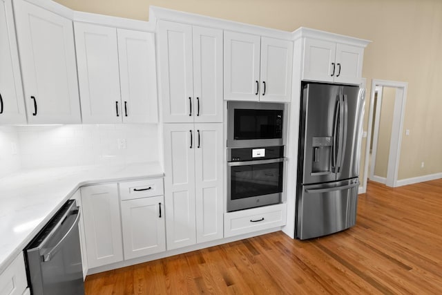 70 Hatch Corner Rd, Meredith, NH 03253 - kitchen with appliances with stainless steel finishes, light wood-type flooring, white cabinetry, decorative backsplash, and baseboards