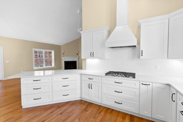 70 Hatch Corner Rd, Meredith, NH 03253 - kitchen with premium range hood, stainless steel gas cooktop, a peninsula, light countertops, and decorative backsplash