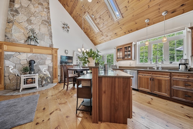 109 Temple Rd, Wilton, NH 03086 - kitchen with stainless steel dishwasher, a sink, a wood stove, light wood-style floors, and high vaulted ceiling