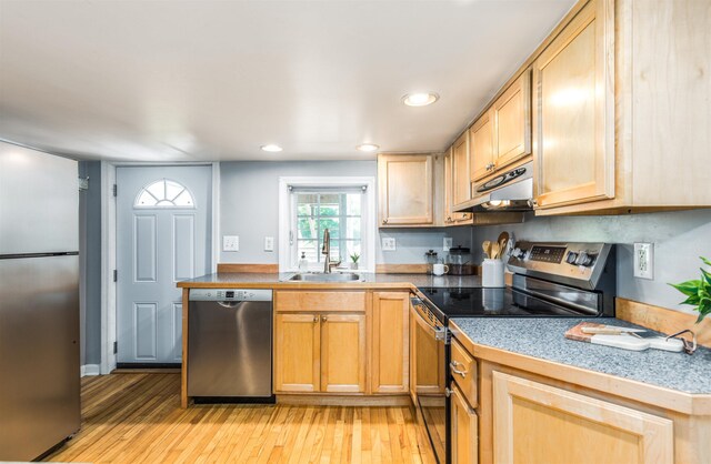 191 Washington St Unit 1, Dover, NH 03820 - kitchen with appliances with stainless steel finishes, a sink, under cabinet range hood, tile countertops, and light wood-style floors