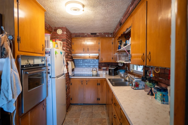 509 Cedar St, Manchester, NH 03103 - kitchen with oven, freestanding refrigerator, a sink, a textured ceiling, and brown cabinetry