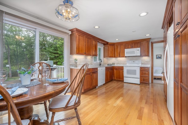 42 Bennett Bridge Rd, Northwood, NH 03261 - kitchen featuring white appliances, decorative backsplash, light wood-style floors, brown cabinets, and a chandelier