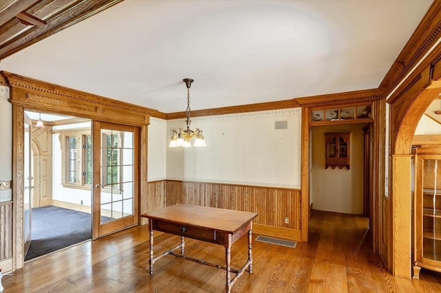98 Sugar Maple Dr, Swanton, VT 05488 - dining area with a wainscoted wall, wood finished floors, a chandelier, wood walls, and crown molding