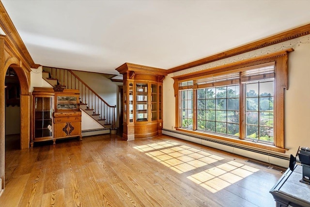 98 Sugar Maple Dr, Swanton, VT 05488 - unfurnished living room featuring baseboard heating, wood finished floors, stairs, arched walkways, and crown molding