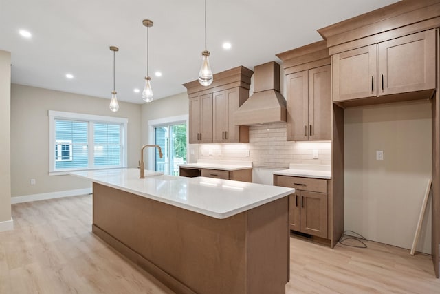 288 Sterling Dr, Laconia, NH 03249 - kitchen with premium range hood, light wood-style flooring, a center island with sink, a sink, and backsplash