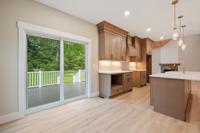 288 Sterling Dr, Laconia, NH 03249 - kitchen with custom exhaust hood, a sink, backsplash, light wood finished floors, and light countertops