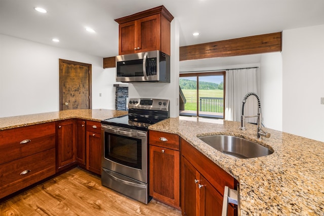 210 Field Rd Unit 44, Stowe, VT 05672 - kitchen featuring stainless steel appliances, a sink, light wood-type flooring, light stone countertops, and a peninsula
