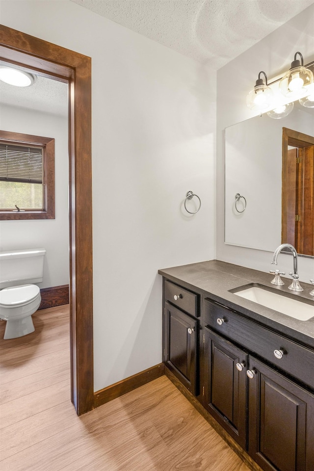 210 Field Rd Unit 44, Stowe, VT 05672 - bathroom with wood finished floors, vanity, toilet, a textured ceiling, and baseboards