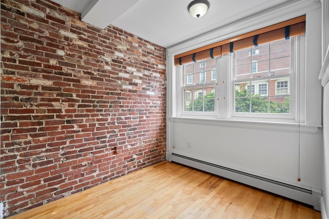 647 Canal St, Manchester, NH 03101 - empty room with a baseboard radiator, brick wall, and wood finished floors