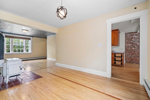 647 Canal St, Manchester, NH 03101 - unfurnished living room featuring a baseboard heating unit, light wood-type flooring, baseboards, and a wood stove