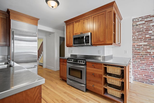647 Canal St, Manchester, NH 03101 - kitchen featuring stainless steel counters, stainless steel appliances, light wood finished floors, brown cabinetry, and a baseboard heating unit