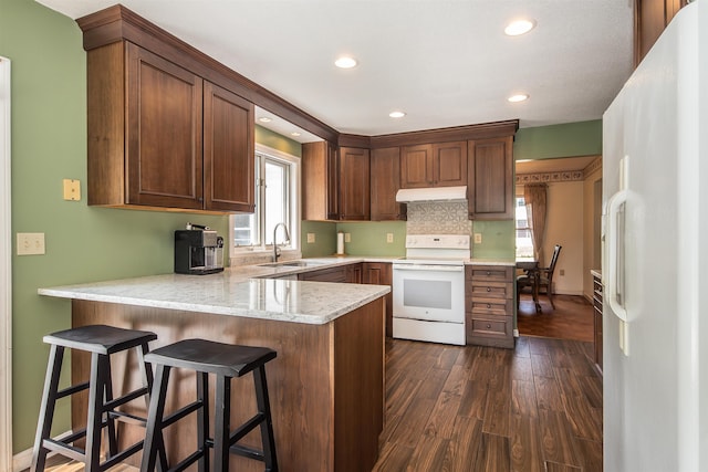 6 Moonbrook Dr, Rutland City, VT 05701 - kitchen featuring white appliances, under cabinet range hood, a sink, a peninsula, and dark wood-style flooring