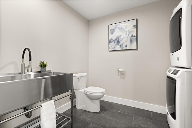 25 Little Bay Dr, Dover, NH 03820 - bathroom featuring estacked washer and dryer, toilet, a sink, baseboards, and tile patterned floors