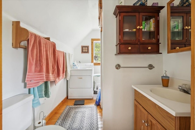 458 Woodcock Rd, Plainfield, VT 05667 - half bathroom featuring toilet, vanity, wood finished floors, vaulted ceiling, and washer and dryer
