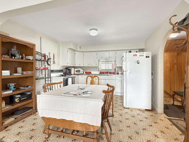 128 Gale St, Canaan, VT 05903 - kitchen with white appliances, arched walkways, white cabinetry, light countertops, and a sink