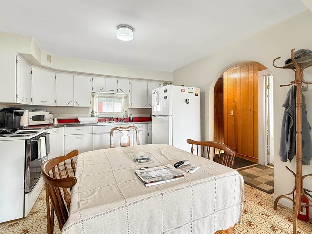 128 Gale St, Canaan, VT 05903 - kitchen featuring white appliances, arched walkways, light floors, white cabinetry, and a sink