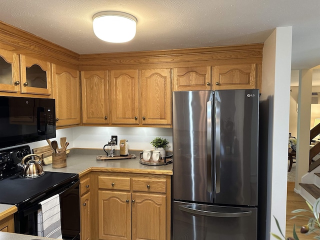11 Pimlico Ct, Bedford, NH 03110 - kitchen with black appliances, brown cabinets, glass insert cabinets, light countertops, and wood finished floors