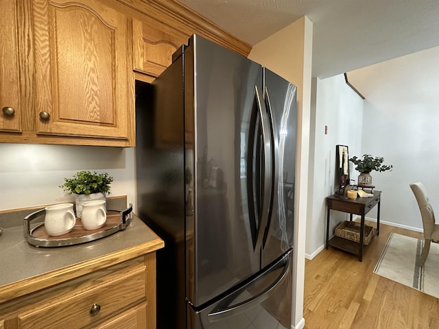 11 Pimlico Ct, Bedford, NH 03110 - kitchen featuring freestanding refrigerator, brown cabinets, light wood-type flooring, light countertops, and baseboards