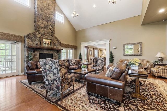 76 Cottonwood Way, Manchester, NH 03102 - living room featuring high vaulted ceiling, wood finished floors, a chandelier, and a stone fireplace
