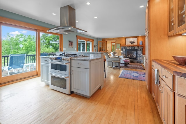 372 Brill Rd, Landaff, NH 03785 - kitchen featuring range with two ovens, island range hood, a stone fireplace, open floor plan, and light wood-style floors