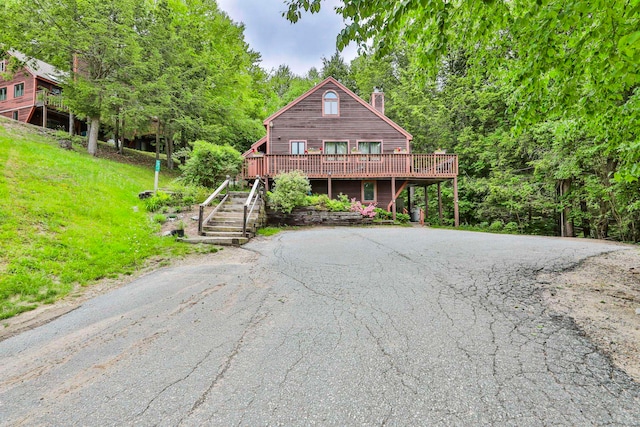 47 Trailside Ln Unit 18, Francestown, NH 03043 - rustic home with a chimney, a wooden deck, driveway, stairs, and a view of trees