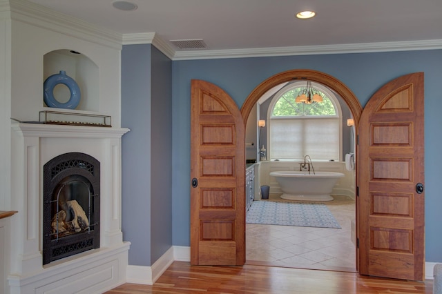 194 Maquam Shore Rd, Swanton, VT 05488 - bathroom with a soaking tub, crown molding, wood finished floors, a fireplace with raised hearth, and recessed lighting