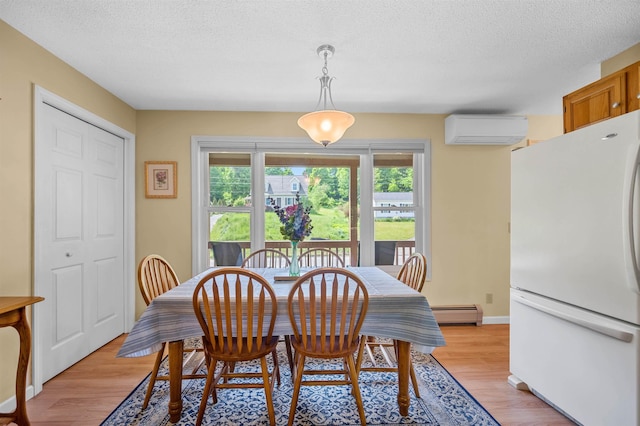 121 Forest Dr Unit 4, Montpelier, VT 05602 - dining space featuring a wall mounted AC, a baseboard radiator, a textured ceiling, and light wood finished floors