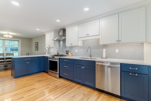 12 Garrison Ln, Madbury, NH 03823 - kitchen featuring appliances with stainless steel finishes, wall chimney exhaust hood, blue cabinets, a peninsula, and recessed lighting