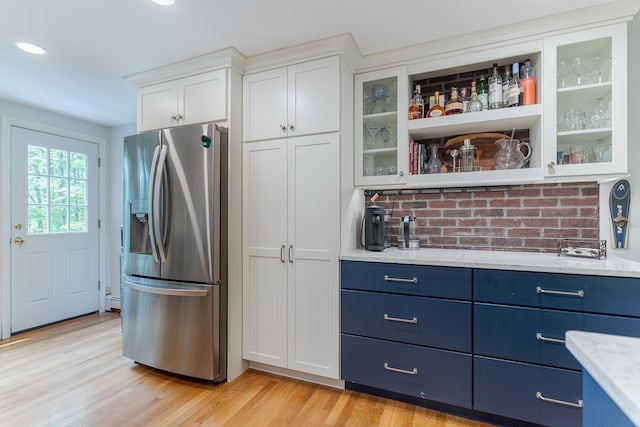 12 Garrison Ln, Madbury, NH 03823 - kitchen with stainless steel fridge with ice dispenser, blue cabinetry, white cabinetry, light wood-style flooring, and glass insert cabinets