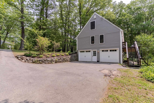12 Garrison Ln, Madbury, NH 03823 - view of side of home with stairs, asphalt driveway, view of scattered trees, and a garage
