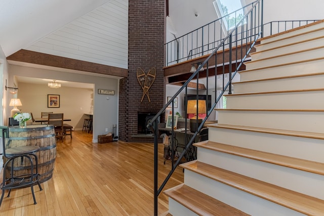 12 Garrison Ln, Madbury, NH 03823 - staircase featuring a high ceiling, wood-type flooring, and a brick fireplace