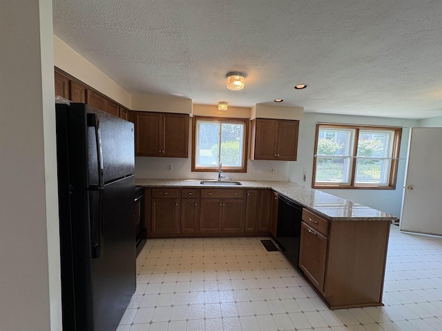 28 Old Orchard Way, Manchester, NH 03103 - kitchen featuring black appliances, a peninsula, a textured ceiling, plenty of natural light, and light stone counters