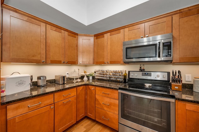 116 Piscataqua Rd Unit C, Durham, NH 03824 - kitchen featuring appliances with stainless steel finishes, light wood-type flooring, dark stone countertops, and brown cabinetry