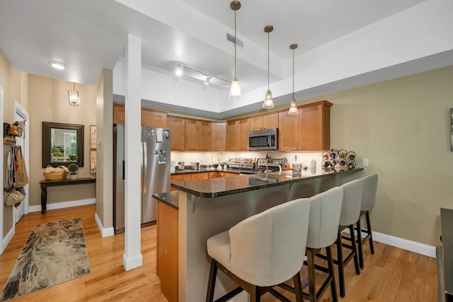 116 Piscataqua Rd Unit C, Durham, NH 03824 - kitchen with stainless steel appliances, a peninsula, light wood-style flooring, a breakfast bar, and brown cabinets