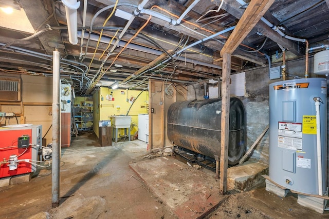 906 N Main St, Laconia, NH 03246 - unfinished basement featuring water heater, oil tank, washer and dryer, and a heating unit