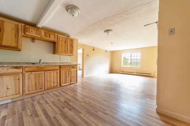 30 Beech St Unit 4B, Bristol, NH 03222 - kitchen with a baseboard radiator, light wood-type flooring, a textured ceiling, open floor plan, and light brown cabinetry