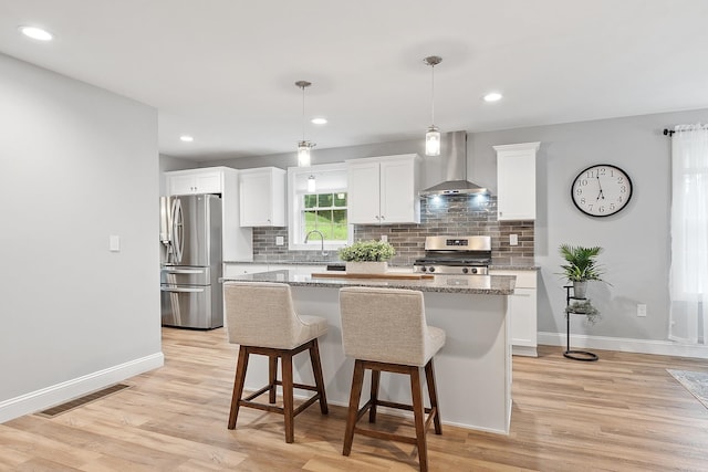 7A Terraceview Dr, Hudson, NH 03051 - kitchen featuring wall chimney exhaust hood, stainless steel appliances, a kitchen island, decorative backsplash, and white cabinets