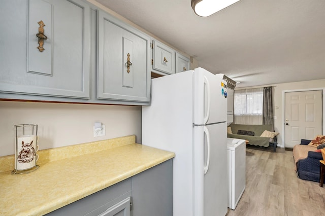 42 Wylie Ct Unit 6, Conway, NH 03860 - kitchen with gray cabinetry, freestanding refrigerator, stacked washer / dryer, light wood-style floors, and light countertops