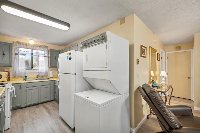 42 Wylie Ct Unit 6, Conway, NH 03860 - kitchen featuring stacked washer / dryer, gray cabinetry, white appliances, a textured ceiling, and light wood-style floors