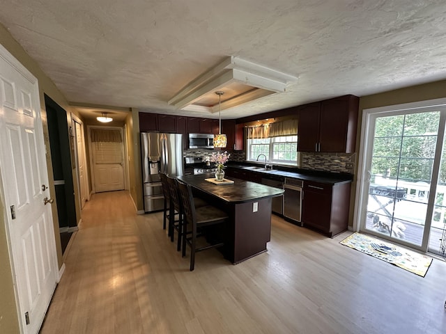 2 Cobblestone Pl, Merrimack, NH 03054 - kitchen with stainless steel appliances, light wood-style floors, tasteful backsplash, a breakfast bar, and a textured ceiling