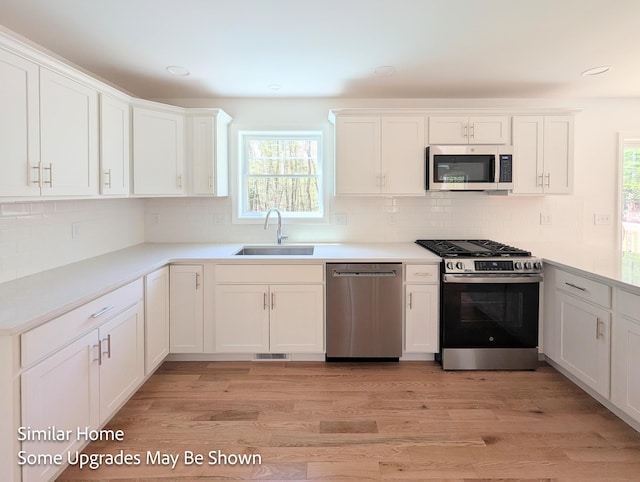 8 Meindl Rd Unit 1, Raymond, NH 03077 - kitchen with stainless steel appliances, white cabinetry, decorative backsplash, light wood-style flooring, and recessed lighting