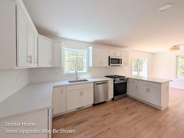 8 Meindl Rd Unit 1, Raymond, NH 03077 - kitchen with appliances with stainless steel finishes, a peninsula, light wood-style floors, white cabinets, and light countertops