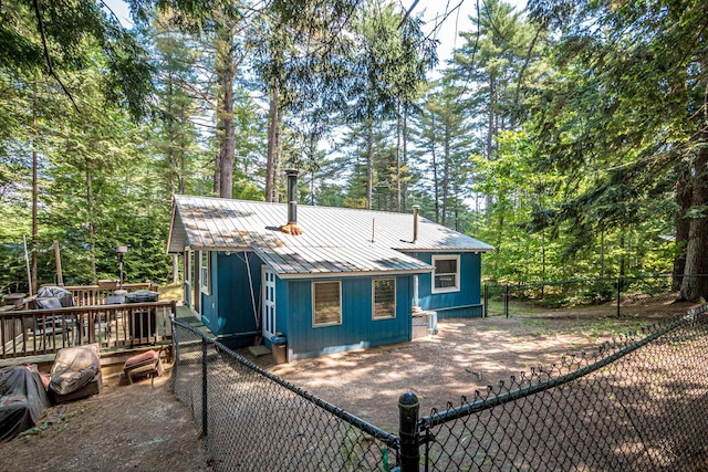 25 Singer Ln, Conway, NH 03813 - back of house with a metal roof, a wooden deck, a fenced backyard, view of wooded area, and driveway