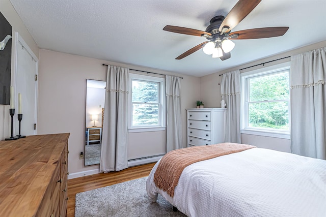 71/2 Olesen Rd, Derry, NH 03038 - bedroom featuring light wood-style floors, multiple windows, a ceiling fan, and a baseboard radiator
