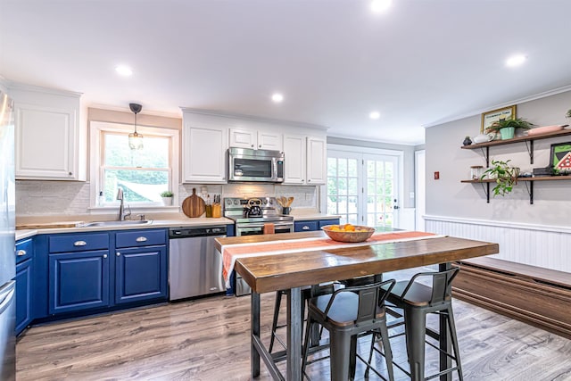 71/2 Olesen Rd, Derry, NH 03038 - kitchen with stainless steel appliances, blue cabinetry, ornamental molding, white cabinets, and light wood-type flooring