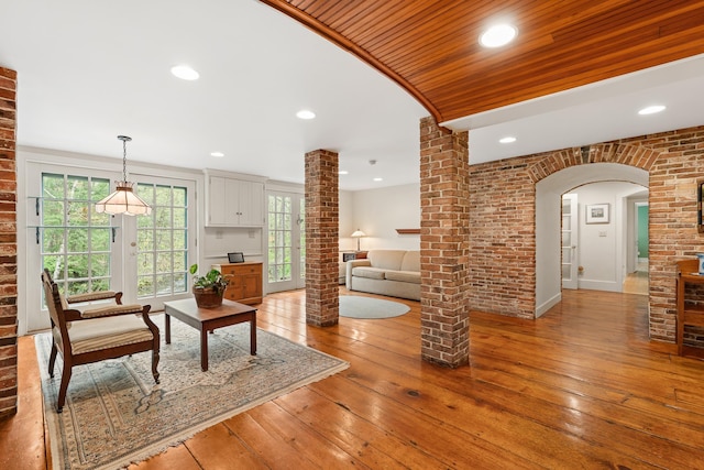 85 Dartmouth College Hwy Unit 204, Lyme, NH 03768 - living area featuring arched walkways, light wood-style flooring, plenty of natural light, ornate columns, and brick wall
