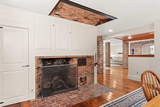 85 Dartmouth College Hwy Unit 204, Lyme, NH 03768 - living room featuring decorative columns, a brick fireplace, recessed lighting, hardwood / wood-style flooring, and brick wall