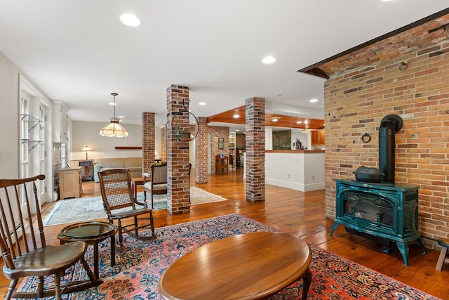 85 Dartmouth College Hwy Unit 204, Lyme, NH 03768 - living area with decorative columns, hardwood / wood-style floors, a wood stove, brick wall, and recessed lighting