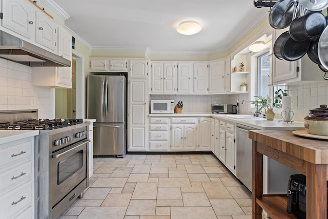 496 Coles Hill Rd, Wells, ME 04090 - kitchen with stainless steel appliances, light countertops, crown molding, white cabinets, and backsplash