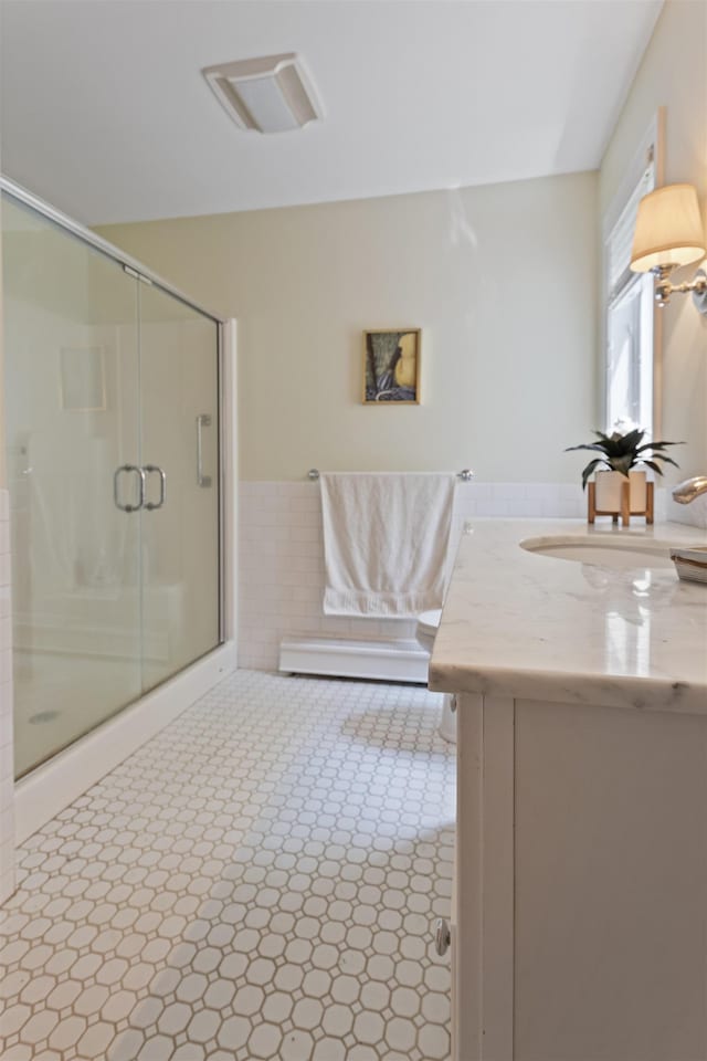 496 Coles Hill Rd, Wells, ME 04090 - bathroom featuring vanity, a stall shower, a wainscoted wall, tile walls, and a baseboard radiator